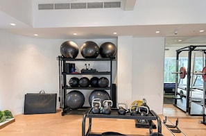 Academia com equipamentos de ginástica, incluindo kettlebells, bolas de medicina e suporte para agachamento.