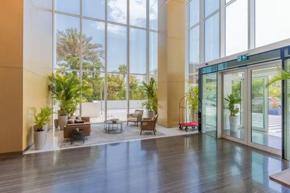 A spacious lobby with large windows, a seating area with sofas and chairs, and a reception desk.