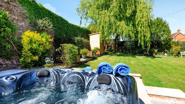 Un jacuzzi con una pared de piedra y follaje al fondo.