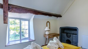 Un dormitorio con cama, ventana, chimenea y lámpara.