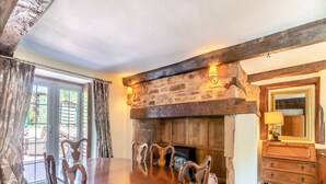Un comedor con una mesa y sillas de madera, una chimenea de piedra y un aparador de madera con un espejo.