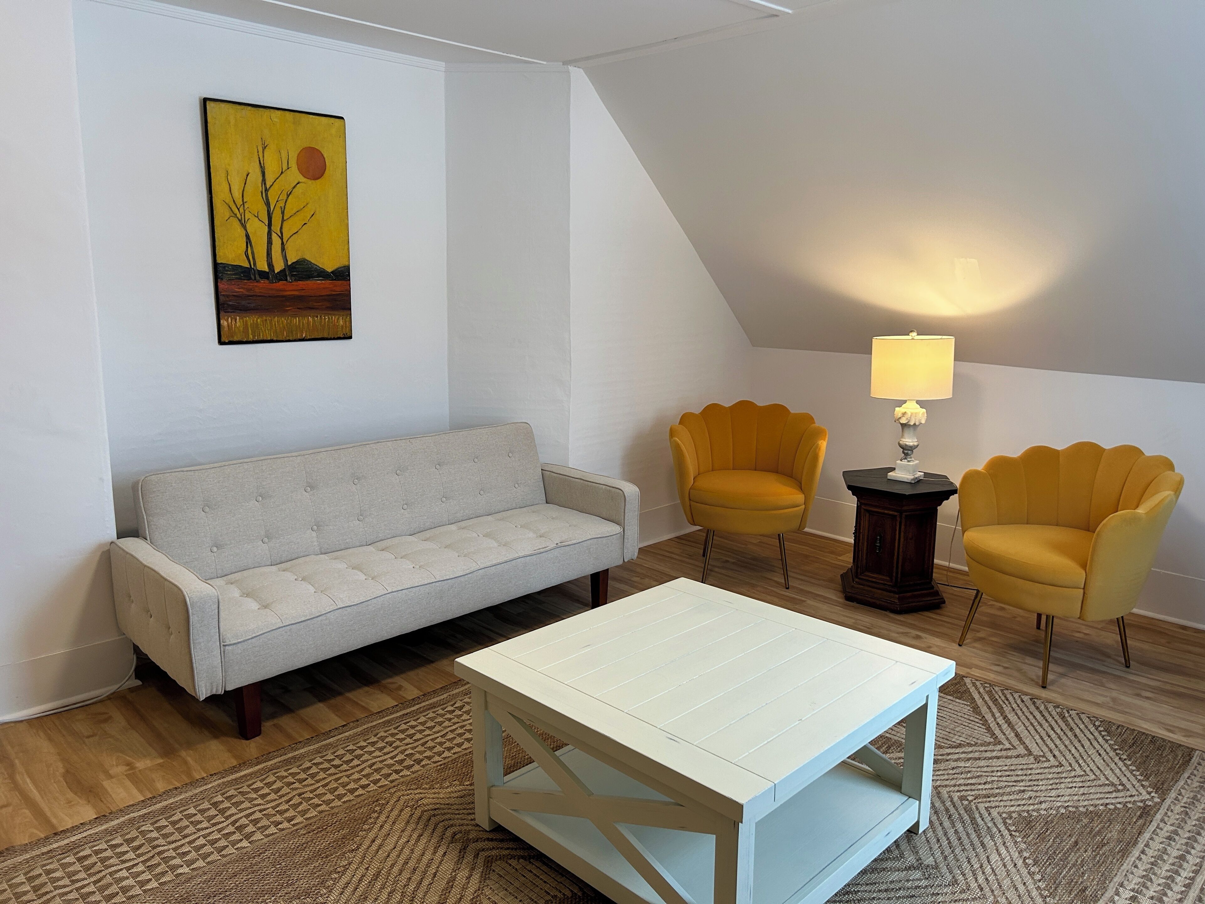Ein Wohnzimmer mit einer Couch, zwei Sesseln, einem Couchtisch und einer Lampe.