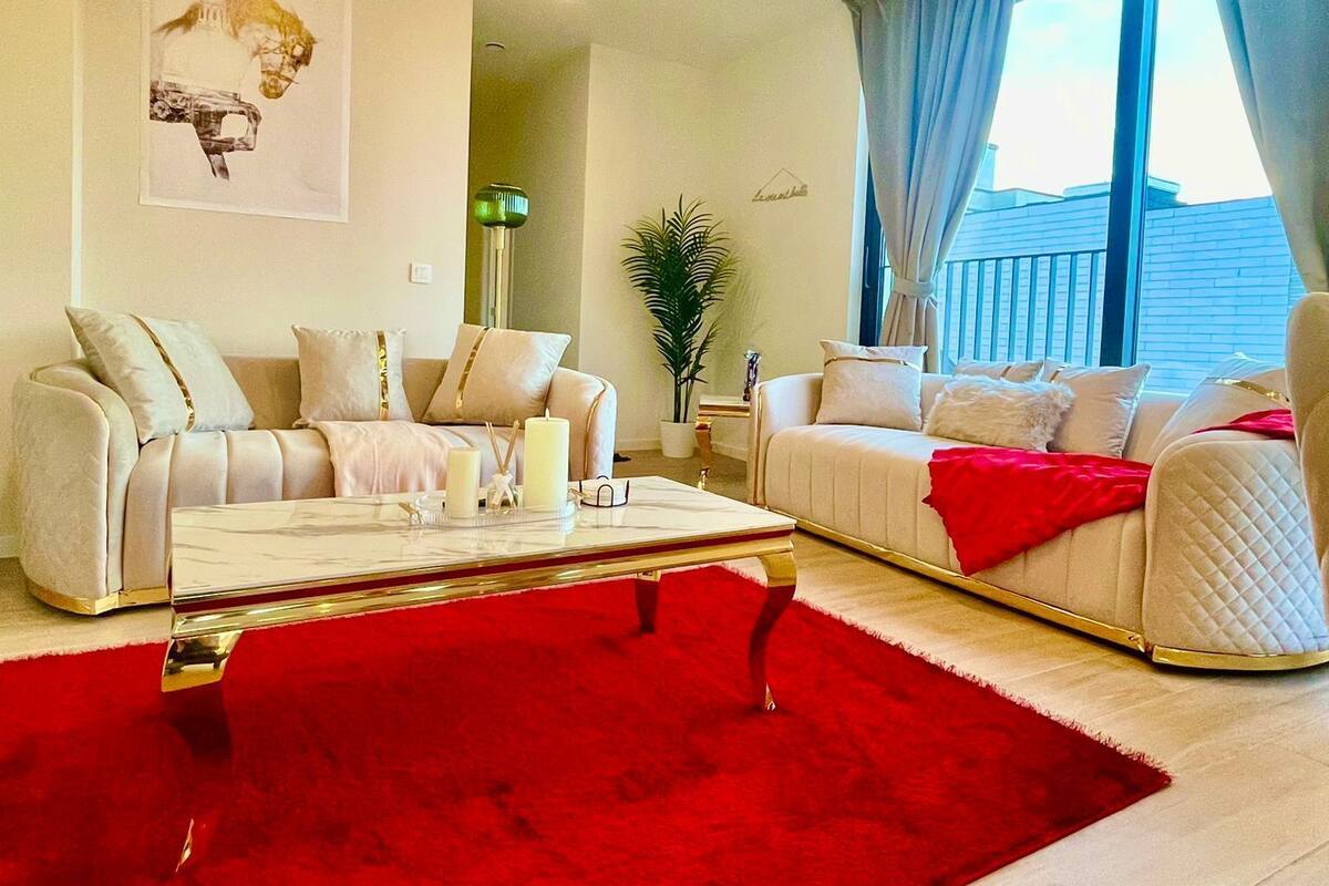 Un salon moderne avec deux canapés, un tapis rouge et une grande fenêtre avec des rideaux.