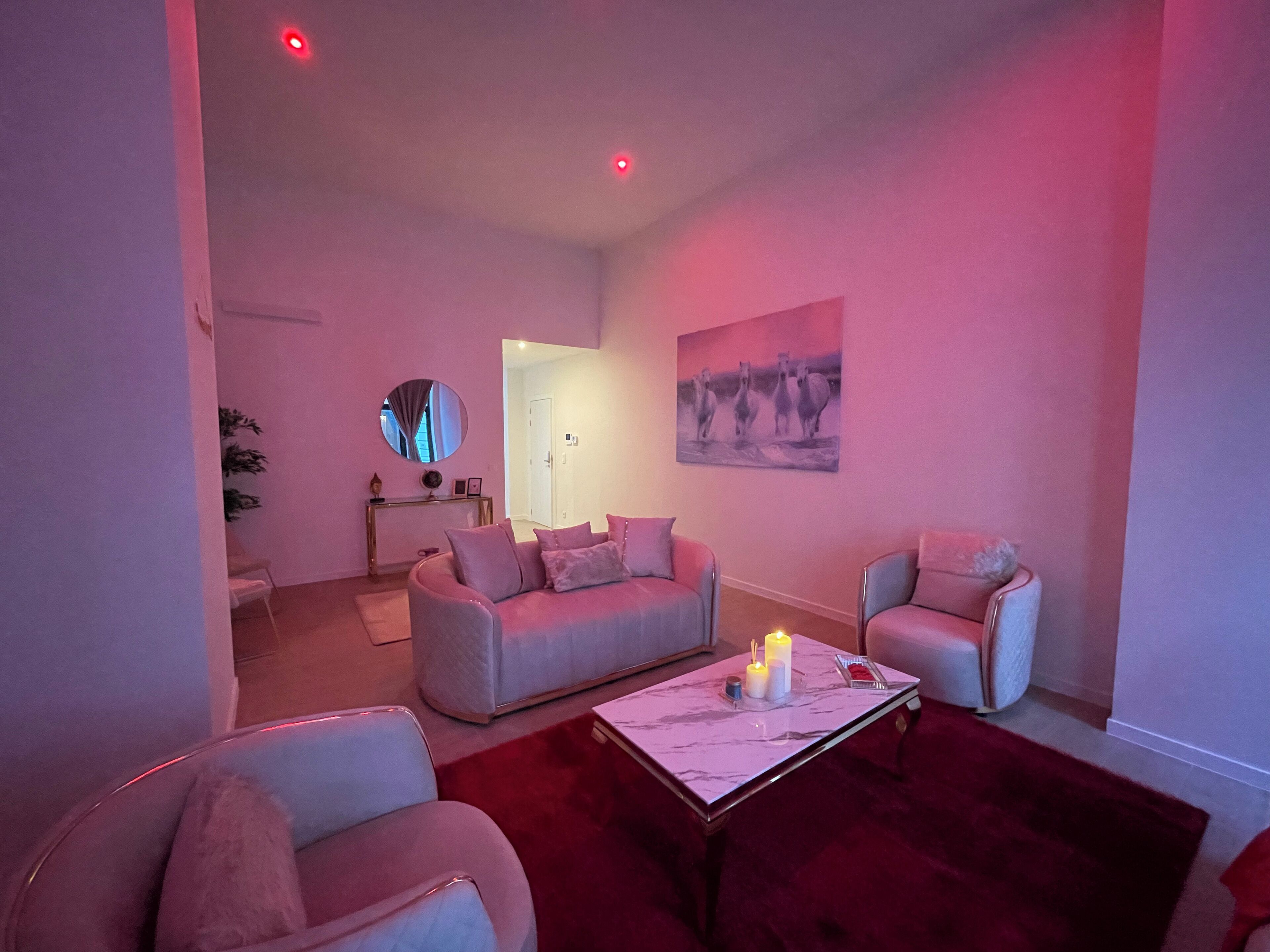 A modern living room with a sofa, armchairs, a coffee table, and a painting on the wall.