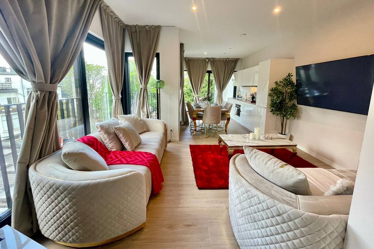 Un salon moderne avec un canapé, un tapis rouge et un coin repas comprenant une table et des chaises.