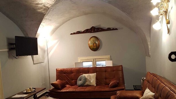 A cozy living room with a vaulted ceiling, a brown leather sofa, a red rug, and a flat-screen TV mounted on the wall. - Bellini house Sangiuliano 132 historic center Catania (Catania)