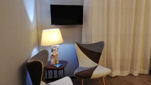 A room with a TV mounted on the wall, a lamp on a small table, and a chair with a unique design. - Bellini house Sangiuliano 132 historic center Catania (Catania)