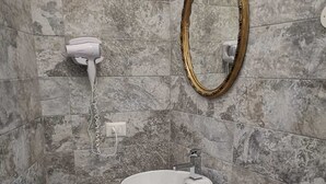 A bathroom with a round sink, a mirror with a gold frame, and a hairdryer on the wall. - Bellini house Sangiuliano 132 historic center Catania (Catania)