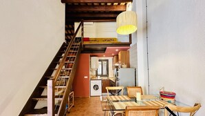 A narrow staircase leading to a kitchen area with a dining table and chairs.