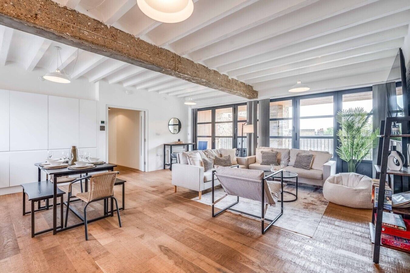 A spacious living area with a high ceiling, a dining table set for four, and a cozy seating arrangement.