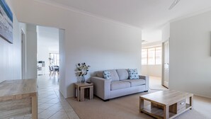 Ein modernes Wohnzimmer mit einer Couch, einem Couchtisch und einem Beistelltisch mit einer Vase.