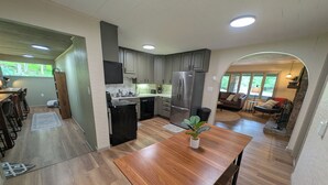 Una cocina moderna con suelo de madera, electrodomésticos de acero inoxidable y una zona de comedor con mesa y sillas de madera.