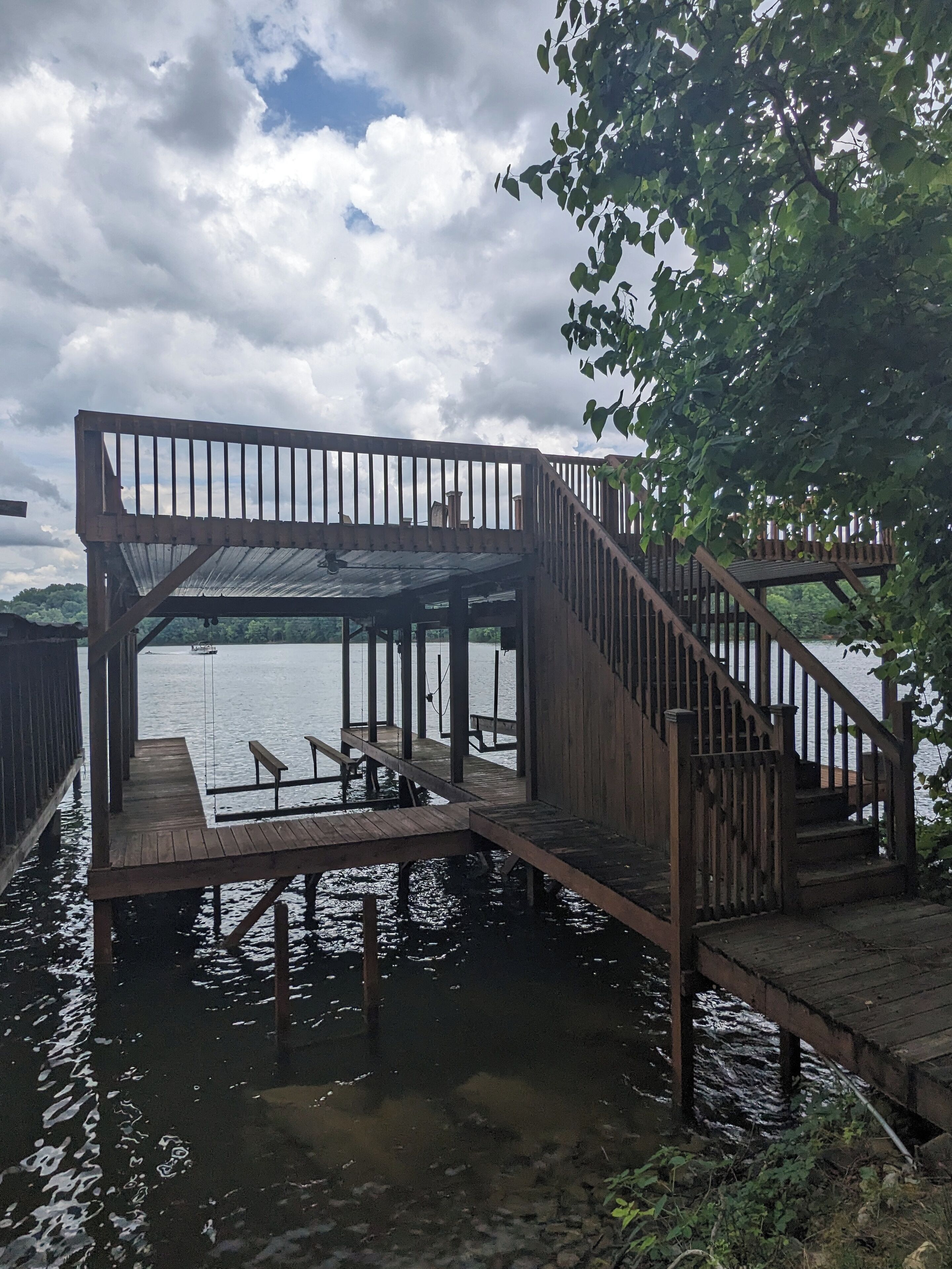 Un muelle de madera con una zona de estar cubierta y una escalera que lleva a una plataforma superior.