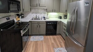 Una cocina con armarios de madera clara, electrodomésticos de acero inoxidable y una isla central.