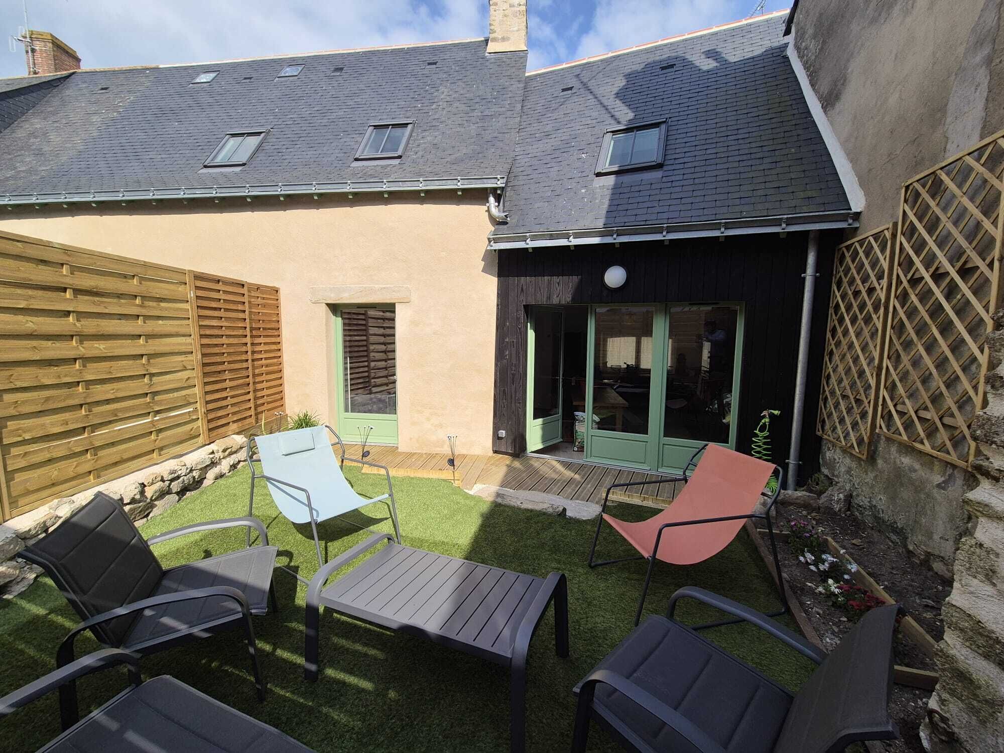Un cortile con patio, un piccolo giardino e una recinzione in legno.