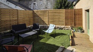 Un jardin avec une clôture en bois, une pelouse et un mur en pierre.