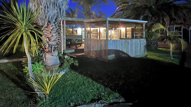 Una casa moderna con un patio de cristal, rodeada de plantas tropicales y una piscina.