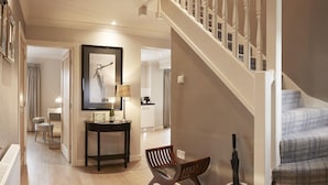 A modern interior with a staircase, a wooden bench, a table with a lamp, and a framed artwork. - The Copper Horse Cottages (Scarborough)