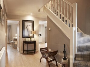 Staircase leads to a beautifully appointed hallway with a bench and artwork.