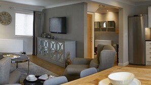 A modern living room with a sofa set, a coffee table, and a dining table with a bowl. - The Copper Horse Cottages (Scarborough)