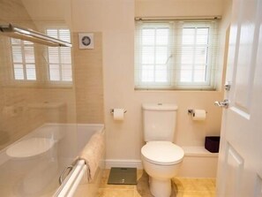 Une salle de bain avec des toilettes, une douche et une fenêtre.