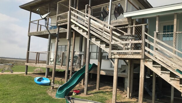 A wooden deck with a slide and a canoe. - Charming 2-bedroom house with a beautiful view, WiFi, AC in Olivia (Port Lavaca)