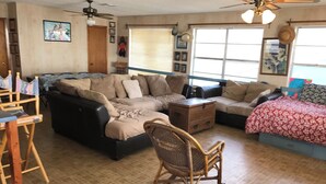 A cozy living room with a sectional sofa, a rocking chair, and a small wooden chest. - Charming 2-bedroom house with a beautiful view, WiFi, AC in Olivia (Port Lavaca)