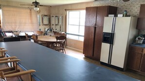 A spacious kitchen with a long counter, wooden chairs, a dining table, and a refrigerator. - Charming 2-bedroom house with a beautiful view, WiFi, AC in Olivia (Port Lavaca)