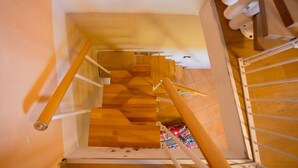 Un escalier en bois avec une rampe métallique, menant à un niveau inférieur.