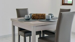 A dining table with four chairs, two grey mugs, a woven basket, and a small window in the background. - Villa the Scent of Oranges (Eboli)