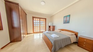 A bedroom with a bed, wooden wardrobe, a nightstand, and a painting of the Golden Gate Bridge.