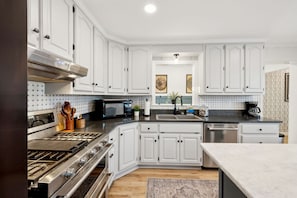 A modern kitchen with white cabinetry, stainless steel appliances, and a central island.