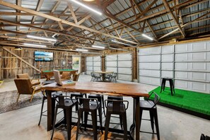 A spacious indoor area with a pool table, bar stools, and a billiards table.