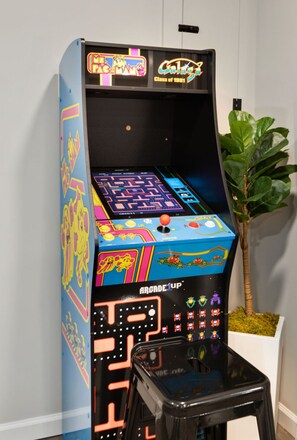 Una máquina recreativa retro con gráficos coloridos y un taburete negro al frente.