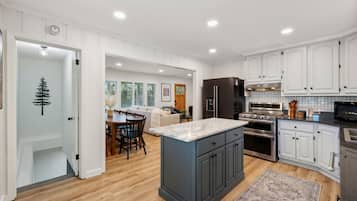 A modern kitchen with white cabinetry, a central island, and a dining area with a wooden table and chairs.