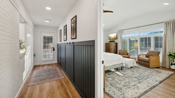 Un dormitorio moderno con una cama, dos sillas, una mesita de noche y una ventana con persianas.