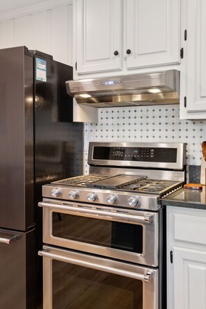 Una cocina con un refrigerador de acero inoxidable, un horno empotrado y una estufa con panel de control digital.