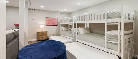 Un dormitorio con literas, una mesita de noche, una lámpara y un otoman azul.