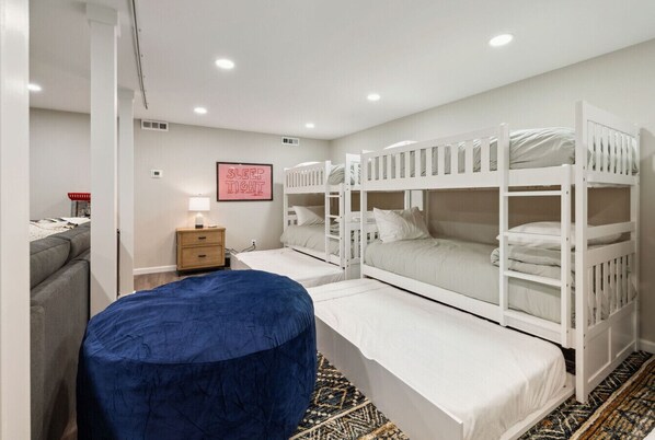 Un dormitorio con literas, una mesita de noche, una lámpara y un otoman azul.
