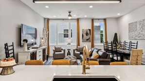 A modern living room with a dining area, a kitchen with a sink, and a large window with blinds. - View of the City, Rooftop Patio, Games and More! (Nashville)