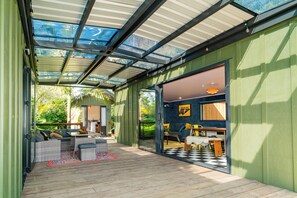 A covered outdoor area with a patio, seating, and a view of the outdoors. - The Funky Escape at The Nest Waihi Beach (Waihi Beach)
