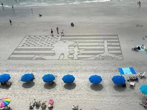 A beach with a large mural, umbrellas, and people. - SHELL YEAH! SURFSIDE 5BR - NEW Heated Saltwater Pool - Sleeps 15+- Walk to Beach (Surfside Beach)