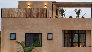A modern two-story building with a balcony, outdoor seating area, and a swimming pool.