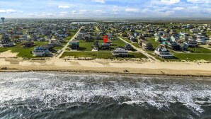 An aerial view of a coastal residential area with houses, a beach, and a lighthouse. - Ocean View~Elevator~PetFriendly~Games~Beach Access (Bolivar Peninsula)