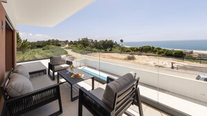 A balcony with outdoor seating, a pool, and a view of the beach and ocean. - Beautiful Sunset Views (Nazaré)