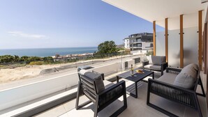 A balcony with a view of the sea, furnished with a sofa, chairs, and a table. - Beautiful Sunset Views (Nazaré)