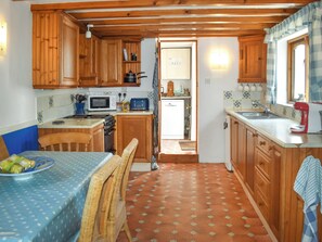 A kitchen with wooden cabinets, a microwave, a stove, a sink, and a dining area with a table and chairs.