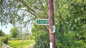 A wooden fence, a signpost with 'Coast Path Tarkra Trail' directions, and a stone wall. - Rivers View - UK49662 (Braunton)