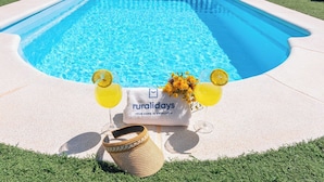 Un espace piscine avec une serviette, un panier en osier et deux boissons garnies de rondelles de citron.