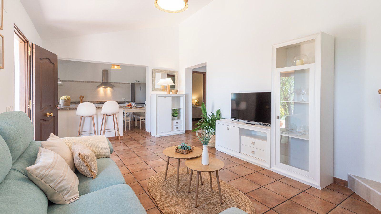 Un salon moderne avec un canapé, un téléviseur et un coin repas comprenant des chaises et une table.